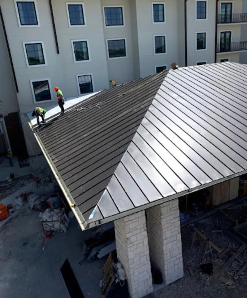 Crew installing standing seam metal roof panels on a commercial project in Chaparral